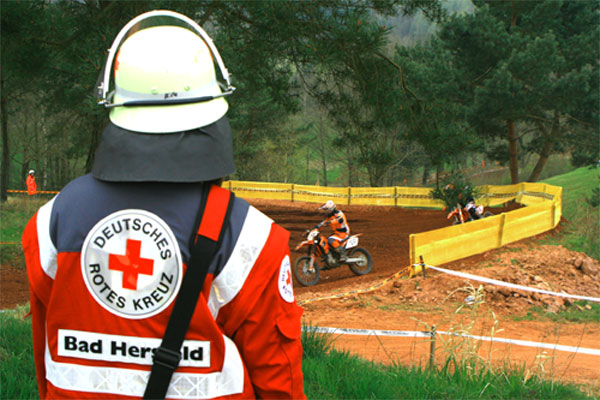 Foto: Mitarbeiter des DRK-Sanitätsdienstes blicken auf das Spielfeld im Stadion.