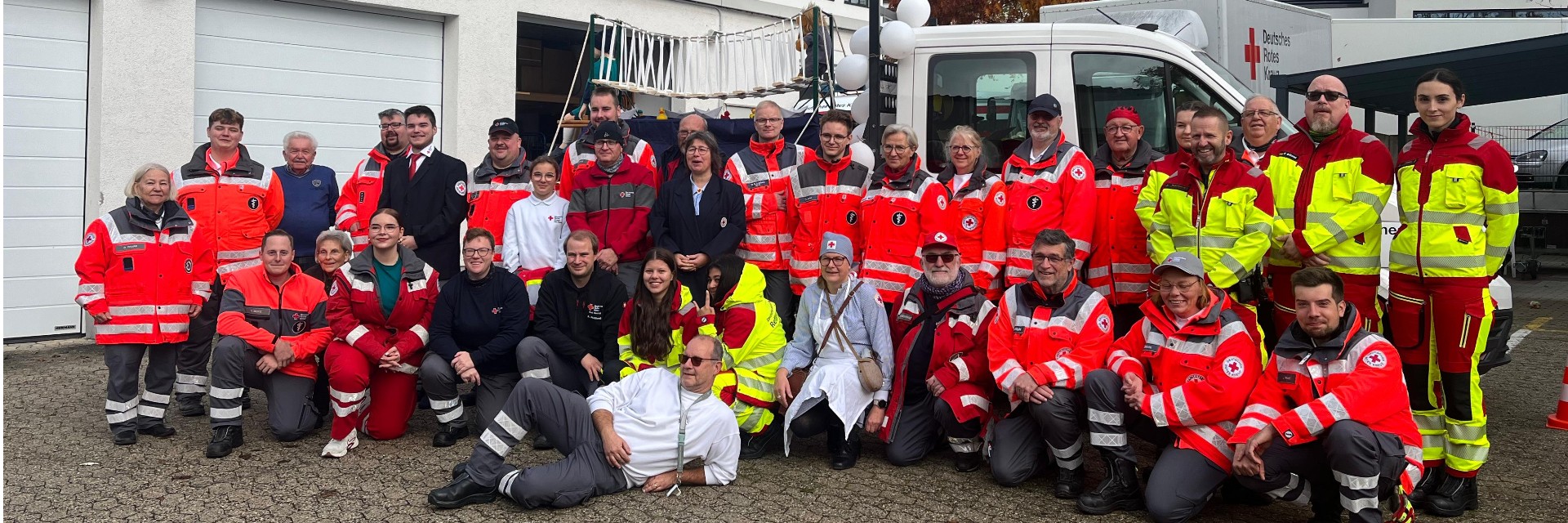 Foto: Mitarbeiter des DRK-Rettungsdienstes stehen vor einem Notarztwagen.