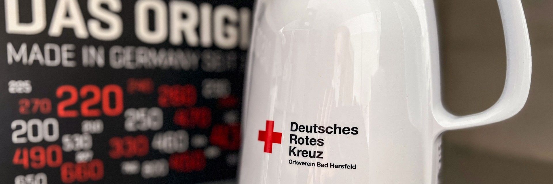 Foto: Eine junge Frau steht mit ihrer Kleiderspende vor zwei DRK-Kleidercontainern.